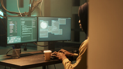 African american spy doing illegal security breach at night, working on cyberbullying to break...