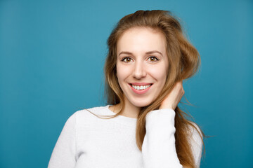 Close-up portrait of a smiling young girl on a blue background