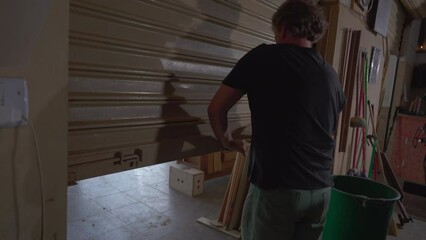 Business owner closing down shop, sliding garage down. Local store closes workshop
