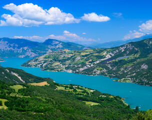 Fototapeta na wymiar Aerial view on blue Lake of Serre-Poncon, reservoir border between Hautes-Alpes and Alpes-de-Haute Provence  departments, one of largest in Western Europe