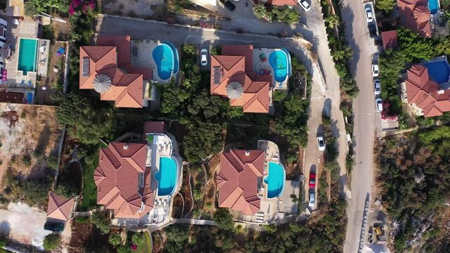 Bird's eye view of red tiled summer houses with swimming pools at Cukurbag Peninsula in Kas, Turkey. White houses and hotels overlooking the Mediterranean Sea
