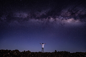 Fototapeta premium Men / boy on the Milky Way. Stargazing at Mauna Loa Observatory Road, Big Island Hawaii. Starry night sky, galaxy astrophotography. 