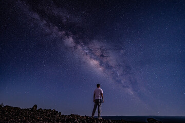 Naklejka na ściany i meble Men / boy on the Milky Way. Stargazing at Mauna Loa Observatory Road, Big Island Hawaii. Starry night sky, galaxy astrophotography. 