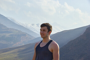 teenager against the backdrop of the mountains after climbing portrait of a cheerful boy in the highlands