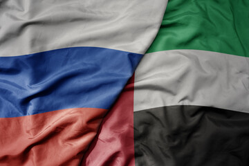 big waving realistic national colorful flag of russia and national flag of united arab emirates .