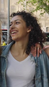 Vertical outdoor video. Beautiful group of young women smiling while walking towards the camera. Female friendship concept with three diverse female friends having fun together in city street.