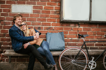 Fototapeta na wymiar Mature couple sitting on a bench after riding bikes in the city