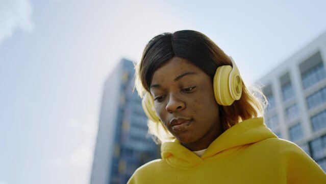 Young African American Woman Listening To Music By Wireless Headphones On Street, Using Mobile App