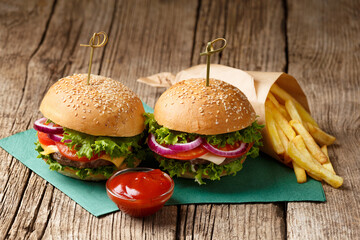 Two burgers, french fries, sauces on a wooden background. Fast food, homemade hamburgers