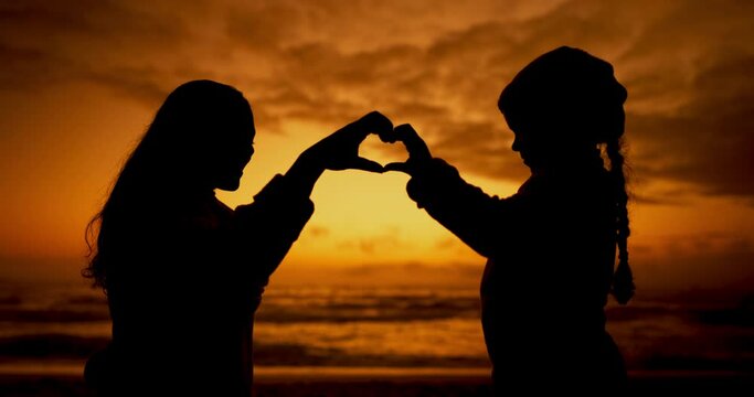 Silhouette, mother and child with heart hands at beach sunset for care, support and affection. Mom, kid at ocean and sign for love, kindness and shadow on vacation, holiday and summer travel at sea.