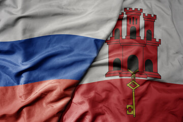 big waving realistic national colorful flag of russia and national flag of gibraltar .
