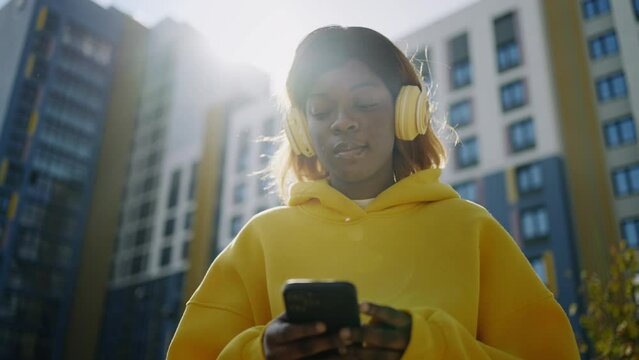 Young Black Female User Of Social Media Standing On Street And Surfing Internet By Smartphone