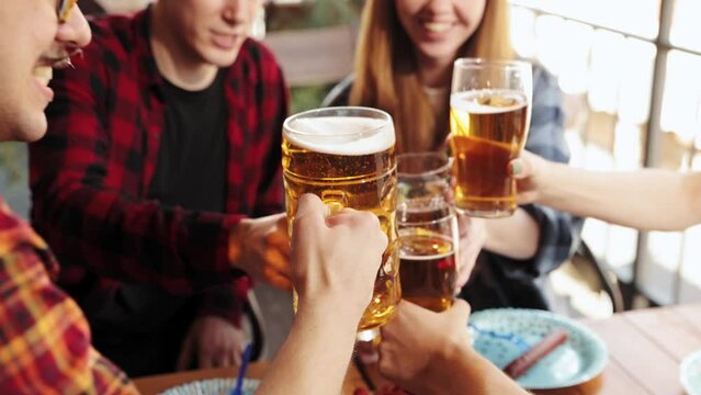 Young smiling people, cheerful friends meeting together in pub, drinking beer, having fun. Celebration, communication. Concept of oktoberfest, traditional taste, friendship, leisure time, enjoyment
