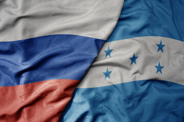 big waving realistic national colorful flag of russia and national flag of honduras .