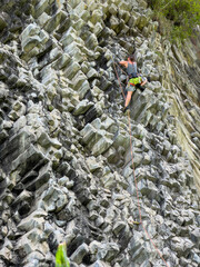 Athletic adrenaline seeking tourist climbs up the unique volcanic rock wall