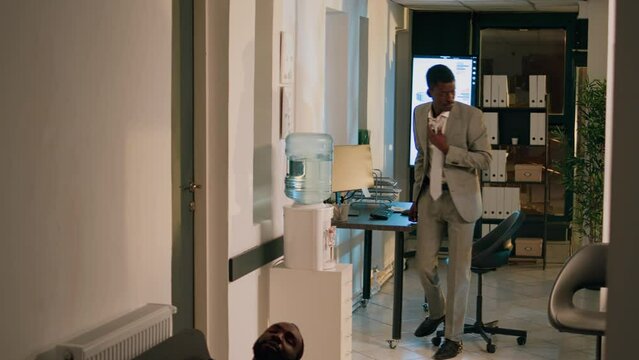 Manager finishing nightshift, ready to go home, catching employee taking nap on office couch. Management executive annoyed by worker slacking off, sleeping at work, thinking of firing him