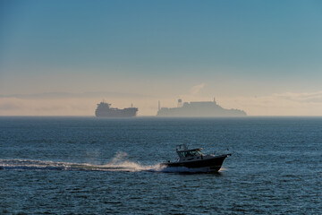 Fishing boat passes in front of oil tanker and Alcatraz on San Francisco Bay