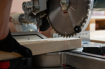 The master cuts the board with a circular saw in the workshop. Close-up of a carpenter's male hands at work.