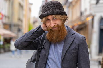 Sad unhappy young bearded man thinks over life concerns, suffers from unfair situation. Problem,...