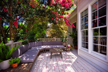 wooden terrace covered in beautiful flower petals under the blooming crape myrtle tree. lounge zone on the summer patio