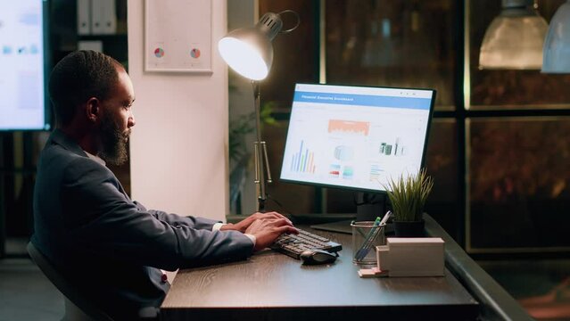 Tired bookkeeper imputing datasets online on computer, trying to keep up with project tasks before deadline. Stressed employee working overnight in office during nightshift