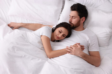 Lovely couple sleeping together in bed at home, top view