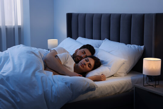 Lovely couple sleeping together in bed at night - Powered by Adobe