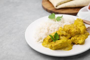 Delicious rice and chicken with curry sauce on light grey table, closeup. Space for text