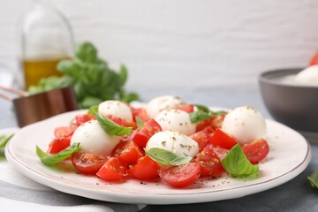 Tasty salad Caprese with tomatoes, mozzarella balls and basil on table, closeup. Space for text