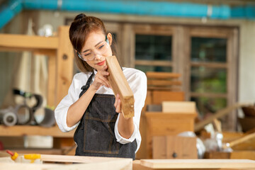 Female carpenter working in wood workshop. Female joiner wearing safety uniform and working in furniture workshop
