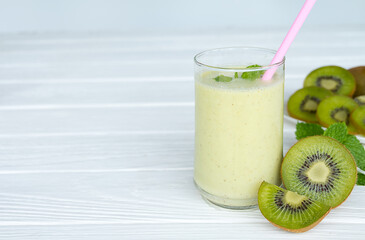 Kiwi yogurt fruit juice smoothie and green kiwi juice drink healthy, delicious taste in a glass for weight loss on a white wooden background.