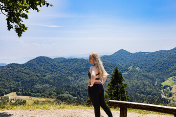 Naklejka na ściany i meble Woman standing on hill and looking at mountains