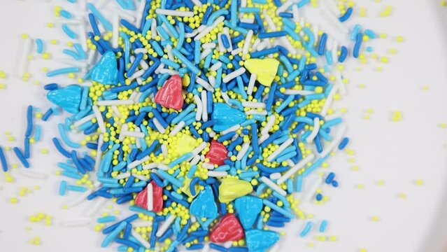  Blue red and yellow rockets, candy balls and sprinkles mix spinning clockwise - shallow depth of field