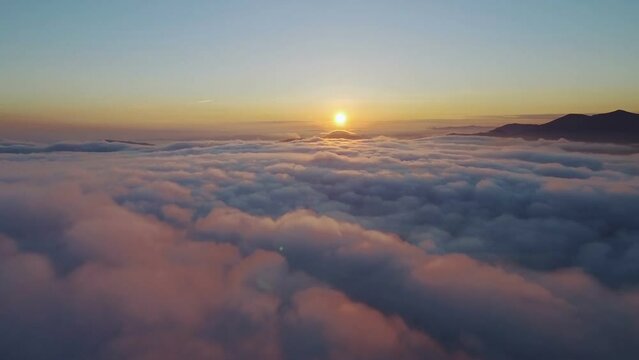 Aerial footage filmed with drone moving through clouds and flying high above the clouds