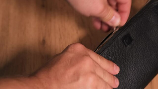 Close up, unzip wallet with euro money with tattooed male hands counting euro banknotes of different denominations budgeting and distributing finances.