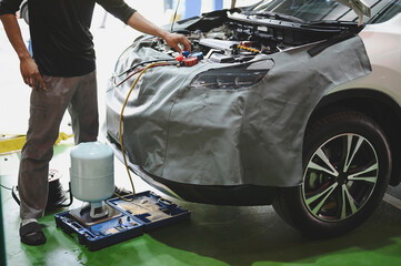 Auto mechanic evacuating and refrigerant recharging the car air conditioning system ,car air...