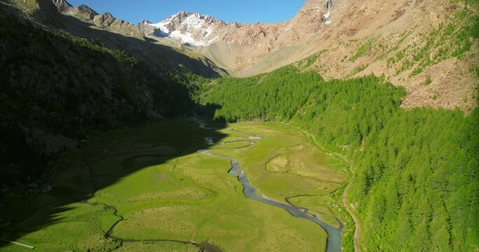 Predarossa plain and Duino river flowing in summer season in Val Masino with mountains in background, Italy. Aerial view