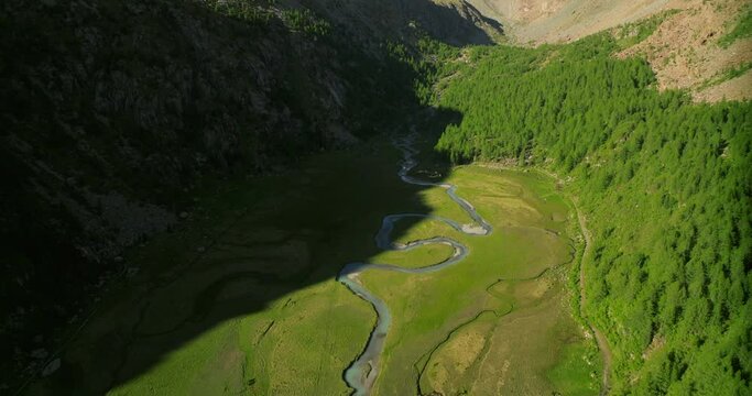 Aerial drone view of Predarossa plain and Duino river flowing in summer season in Val Masino, Italy