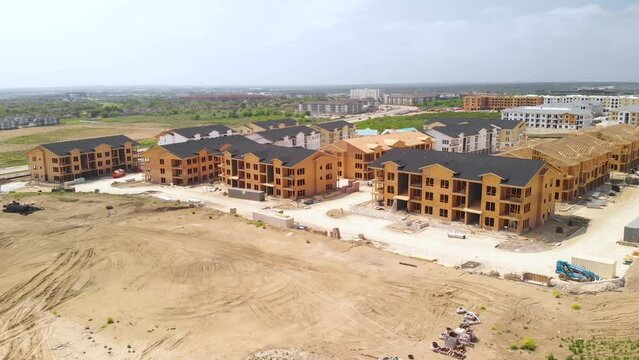 Aerial Drone View of Apartment Homes, Roofs, Trusses, Cranes, Boom Lifts, Tractors, Roads, Cars, Traffic - Residential Building Construction Site In Austin, Texas, USA