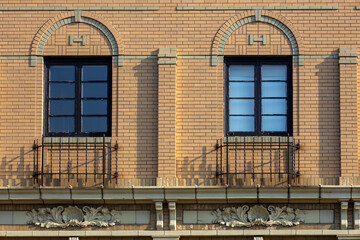 Full frame texture background of a beautiful beige color early 20th century American style brick wall facade with decorative arched window frames