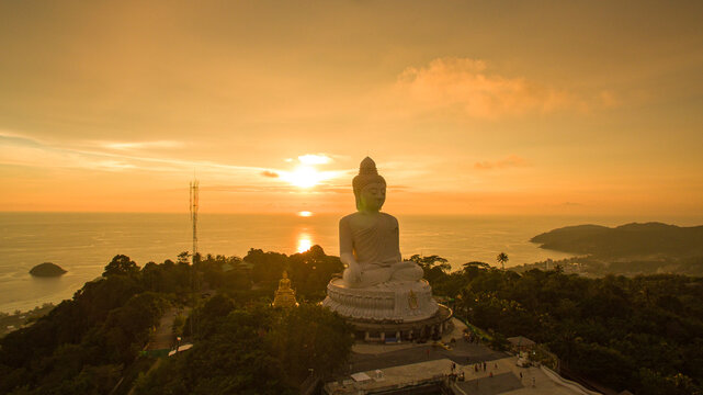 .aerial view Phuket big Buddha in beautiful sunset..amazing sun shines through the yellow clouds impact on golden sea surface.The beauty of the statue fits perfectly with the charming nature..
