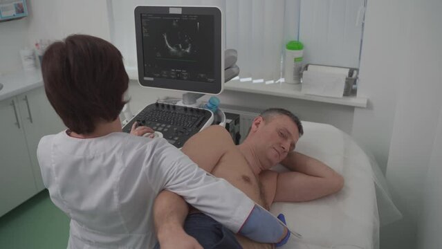 Doctor doing a doppler sonography a male patient in a cardiology clinic. Cardiologist performing an ultrasound examination at the cardiovascular hospital. Echocardiography procedure.