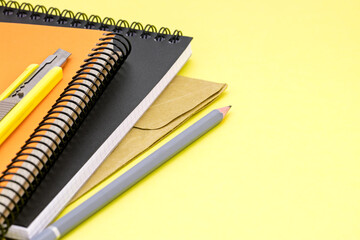 yellow writing desk background with colorful notebooks, pencil, envelope and letter opener