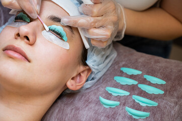 The master removes the composition for lamination from the client's eyelashes with a cotton swab. Eyelash perm procedure.