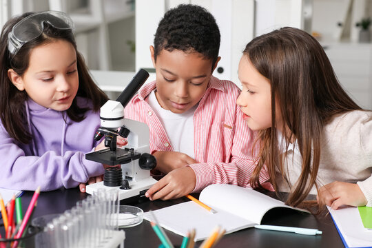 Little children with microscope studying Chemistry in science classroom