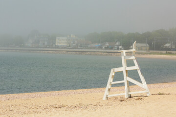 Empty lifeguard chair in the sand of a crescent beach.