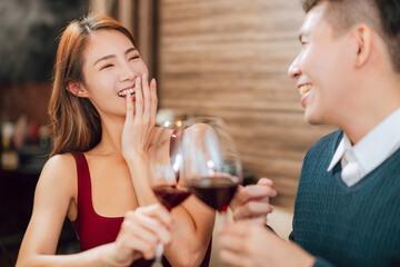 Young happy couple celebrating and toasting with wine glasses in  restaurant.