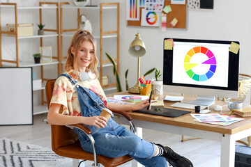 Female graphic designer with cup of coffee working at table in office
