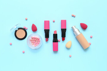 Decorative cosmetics with makeup sponges on blue background