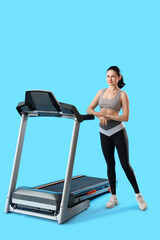 Beautiful woman with treadmill on blue background